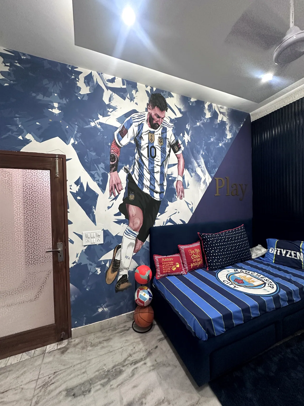 Wide view of the football-themed bedroom, feature mural and blue bed