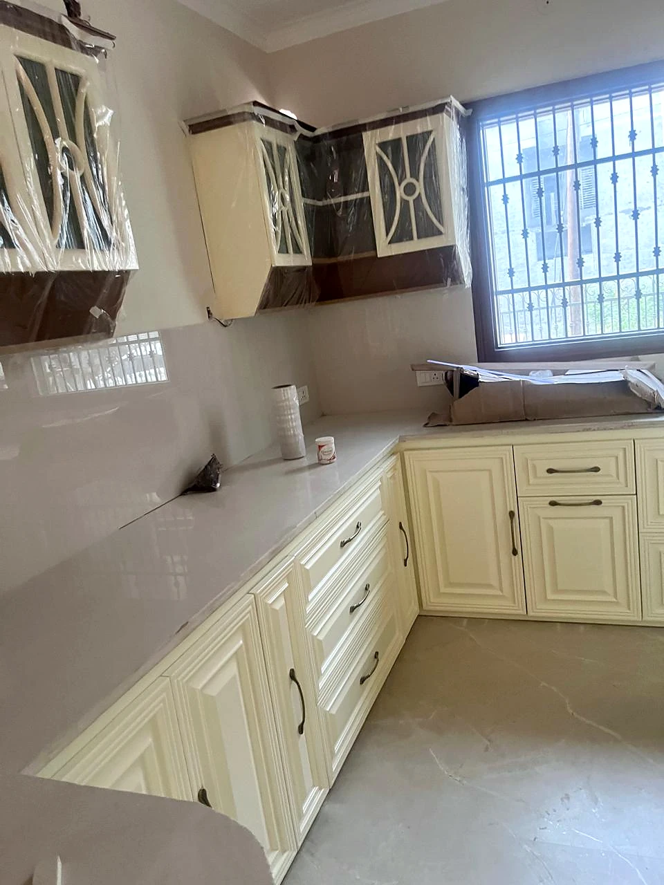 Long kitchen counter with pale lower cabinetry and a nearby window
