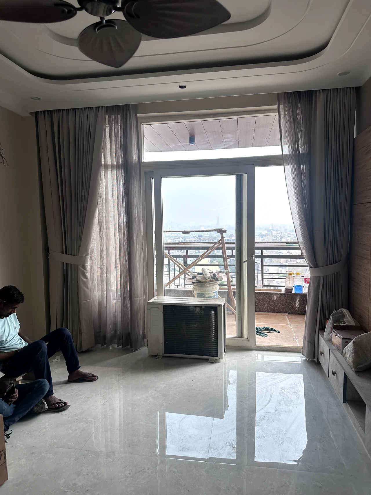 Living area opening towards the balcony, with daylight and full-height curtains