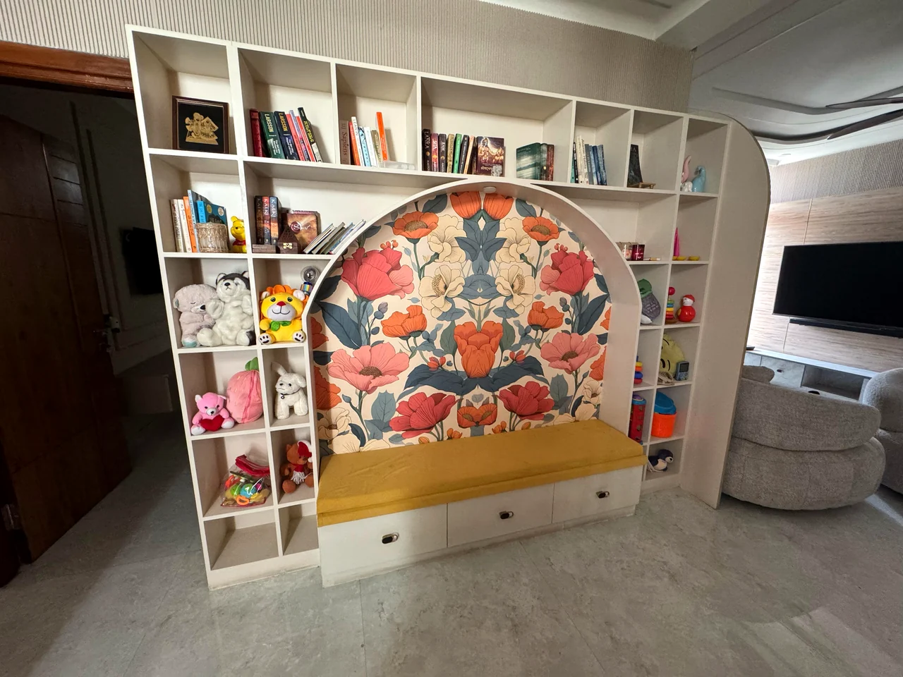 Built-in reading nook with arched floral upholstery and surrounding bookshelves